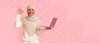 © Prostock-studio - A woman wearing a headscarf stands against a colored background. She holds a laptop in one hand and shows an ok sign with her other hand. The scene captures a moment of joy and success.