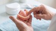 © edojob - Senior hands examining full denture for daily oral care