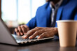 © DC Studio - African american person typing on digital device at desk in modern workspace. Selective focus on hands inputting information for business project on laptop with coffee cup placed nearby on table.