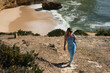 © Angelov - Strong and serene woman holding a yoga mat, walking barefoot along the shoreline in morning light. Coastal wellness and active lifestyle mood.