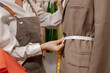 © PHOTO4U - Fashion designer selecting fabric and measuring material while planning clothing design in a creative studio, developing new apparel ideas for fashion production and tailoring work.