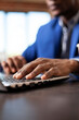© DC Studio - Closeup of hands of african american employee typing on laptop at startup office desk. Black male individual updating company research data using digital technology for work tasks.