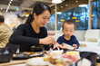 © leungchopan - Mom helping baby eat food at restaurant table