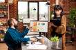 © DC Studio - Young woman stands in front of colleague, holding clipboard and confidently explaining project updates. Supportive bearded man listening to female coworker, ready to collaborate on company research.