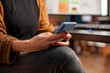 © DC Studio - Selective focus on hands of caucasian woman texting on smartphone while seated at office desk. Closeup of female employee holding mobile device, browsing social media during working hours.