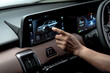 © Vlafy Studio - Close up of driver hand interacting with infotainment touchscreen displaying car interface and connectivity features inside modern vehicle dashboard.