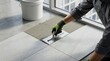 © Helen - Construction worker carefully laying down a new tile with adhesive using a trowel