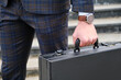 © Teodor Lazarev - Business professional carries briefcase while wearing suit in a corporate setting during daytime