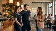 © Muhammad - Smiling female customer talking to two happy cafe staff in aprons at a modern coffee shop
