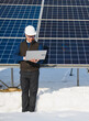 © Serhii - Engineer checking solar panels during winter with laptop