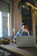 © Teodor Lazarev - Man concentrating, working remotely from home on a laptop, analyzing data, making notes, and planning his business strategy in a modern apartment