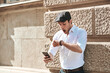 © Teodor Lazarev - Young man realizing being late, looking at his wristwatch and smartphone with a shocked expression, experiencing urgency and time pressure on a city street