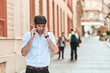 © Teodor Lazarev - Stressed businessman suffering from headache and migraine while talking on smartphone on city street, experiencing mental pressure and urban lifestyle challenges
