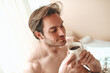 © Teodor Lazarev - Young shirtless man with closed eyes is deeply savoring the aromatic steam rising from his warm coffee cup, embracing a calm and mindful start to his morning ritual
