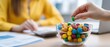 © ZinaZaval - A hand reaches for colorful candies from a bowl on the desk while a young man works on a laptop with papers near him