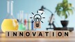 © NoBabi Lebas - Wooden blocks spelling Innovation with a glowing light bulb icon in a laboratory setting