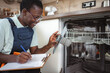 © Jelena - Technician inspecting dishwasher filter and taking notes on clipboard