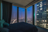 A bedroom located in a tall building offers a view of the city skyline at night. The lights from the streets and buildings create a vibrant atmosphere outside the large windows