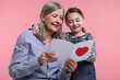 © New Africa - Little girl greeting her grandmother with holiday card on pink background