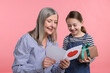 © New Africa - Little girl greeting her grandmother with holiday card and gift on pink background