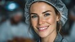 © Anuson - A cheerful young woman with a hair net smiles confidently in a food processing facility, showing her dedication to food safety standards.