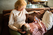 © Geber86 - Senior woman and teenage girl relaxing on sofa at home with smartphone