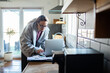 © Geber86 - Woman managing finances on laptop in home kitchen