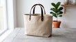 © Rakib - Beige Canvas Tote Bag with Brown Leather Handles on Wooden Table