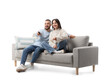 © Pixel-Shot - Young couple watching TV on grey sofa against white background