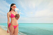 © New Africa - Attractive woman in swimsuit holding refreshing cocktail on beach near sea