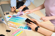 © Pixel-Shot - Team of female graphic designers working with computer, mobile phone and color palettes at table in office, closeup