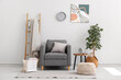 © Pixel-Shot - Interior of stylish living room with armchair, ladder, houseplant, coffee table and clock hanging on white wall