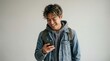 © Halim Karya Art - Smiling Asian male college student holding smartphone against plain background