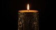 © Nishat - A lit candle with an ornate design on a black background
