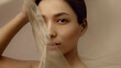 © Lustre Art Group  - Elegant beauty portrait of Korean woman partially covered by translucent beige silk fabric symbolizing softness and modern luxury aesthetics for cosmetics advertising and beauty campaigns.