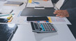 © Kansuda - business documents on office table with tablet, smart phone and laptop and two colleagues discussing data