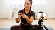 © Lucianastudio - Woman fitness influencer reviews protein powder on camera for online video content