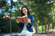 © Parichat - Young asian business woman enjoying reading book outdoors