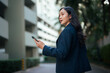 © Parichat - Asian executive woman navigating city street with smartphone