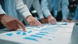 © Udan - Multiple business professionals collaborate while analyzing printed reports displaying data visualizations.