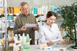 © JackF - Woman employee at counter with computer sells pills and ointments to senior male customer upon request. Everyday life at pharmacy, consulting clients.