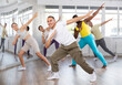 © JackF - European guy teaches sequences of movements, actions during dance lesson, trains to doing elements of RnB dance, enjoys active hobby to music. Multinational group rehearsal, dance choreography coach