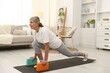 © New Africa - Senior woman exercising with yoga blocks at home. Fitness and sport