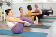 © JackF - Girl coach and multinational group of students perform Paripurna Navasana during workout. Hatha Yoga lesson for beginners, active lifestyle, physical activity