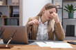 © New Africa - Woman feeling fatigue at wooden desk in office