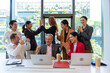 © tonjung - Multiracial euphoric business team people give high five at office table with laptop, happy excited diverse work group engaged in teambuilding teamwork