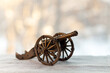 © PhotoBank - A miniature antique cannon on a light surface with blurred background for historical concepts and decorative purposes