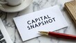© Rakhman - Capital Snapshot card with pen and laptop sitting on table, flat lay shot, corporate lifestyle, business, accounting, financial, banking