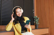 © crizzystudio - Asian woman enjoying music with headphones and smartphone