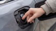© Andre Jovi - Hand opening fuel tank cap of silver car for refueling
